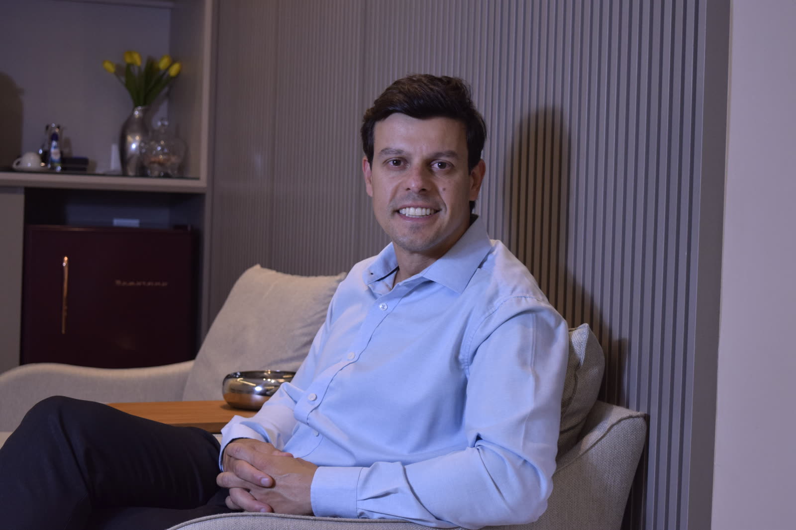 Dr. Ricardo Dolci sentado no consultório, sorrindo