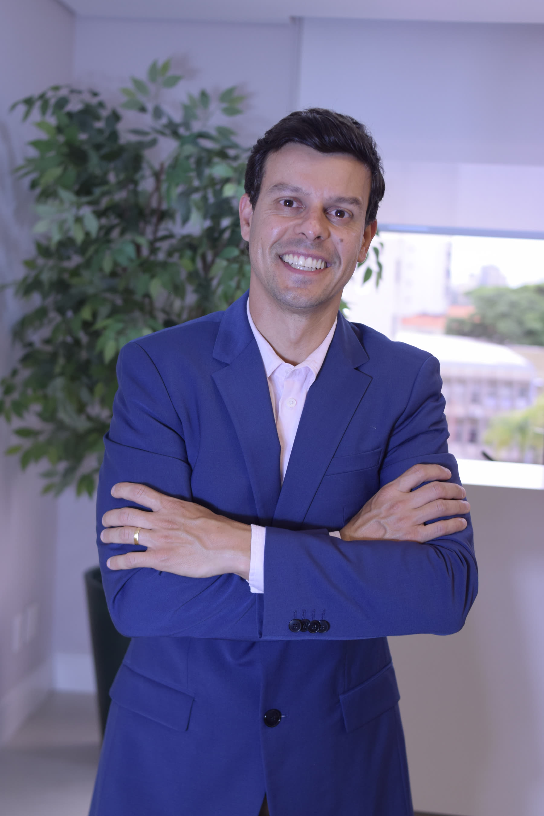 Dr. Ricardo Dolci em pé, de braços cruzados